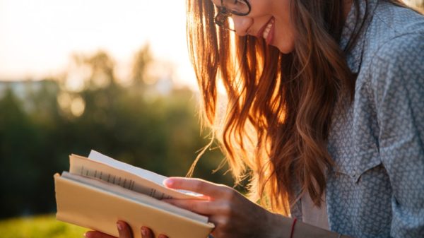 Smiling brunette woman in eyeglasses reading book
